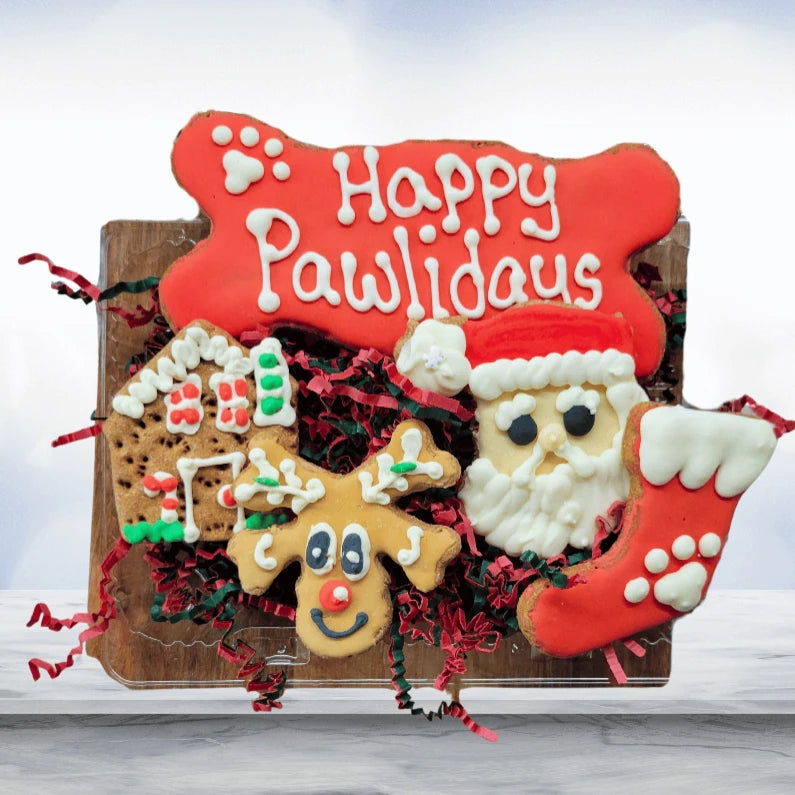 A Pawliday treat box with a Happy Pawlidays bone, Santa, reindeer, stocking and gingerbread house cookies